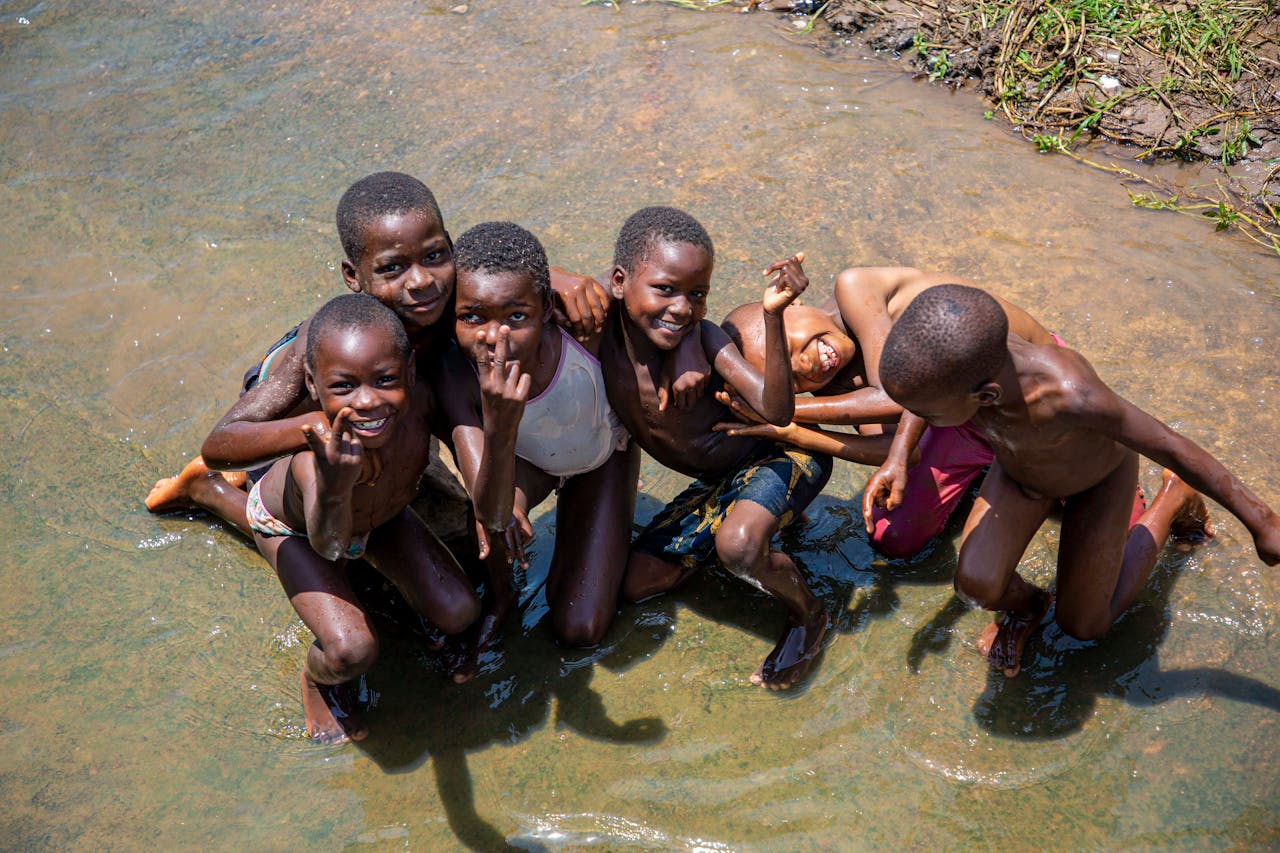 Group of children having fun in shallow water, showcasing their joy and friendship in the sunshine.