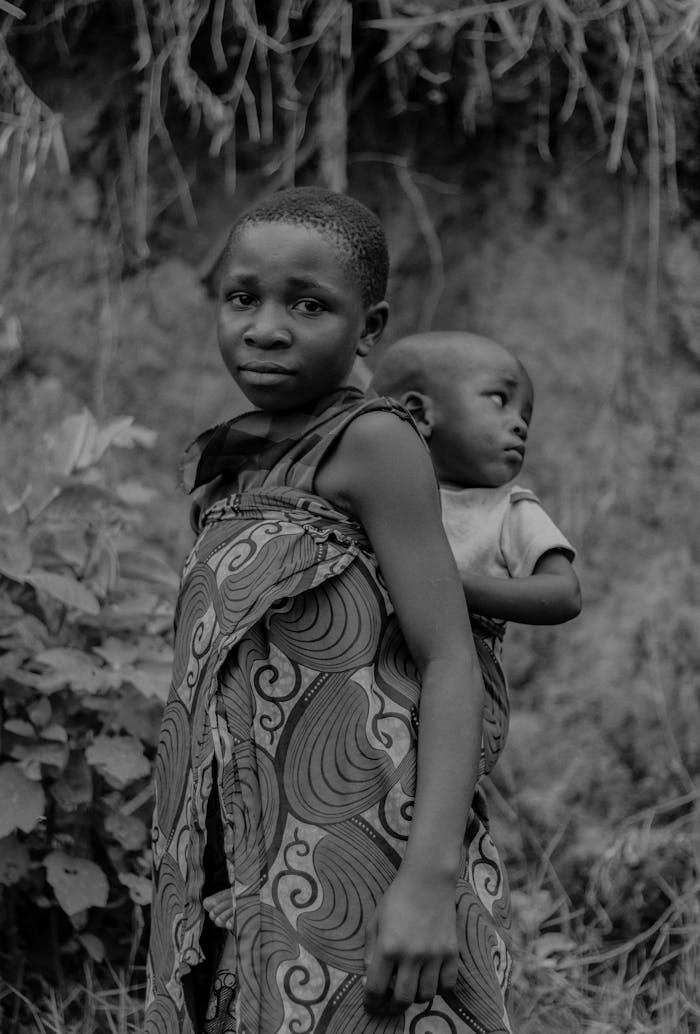 A compelling portrait of siblings standing outdoors in a natural setting, displaying bond and culture.